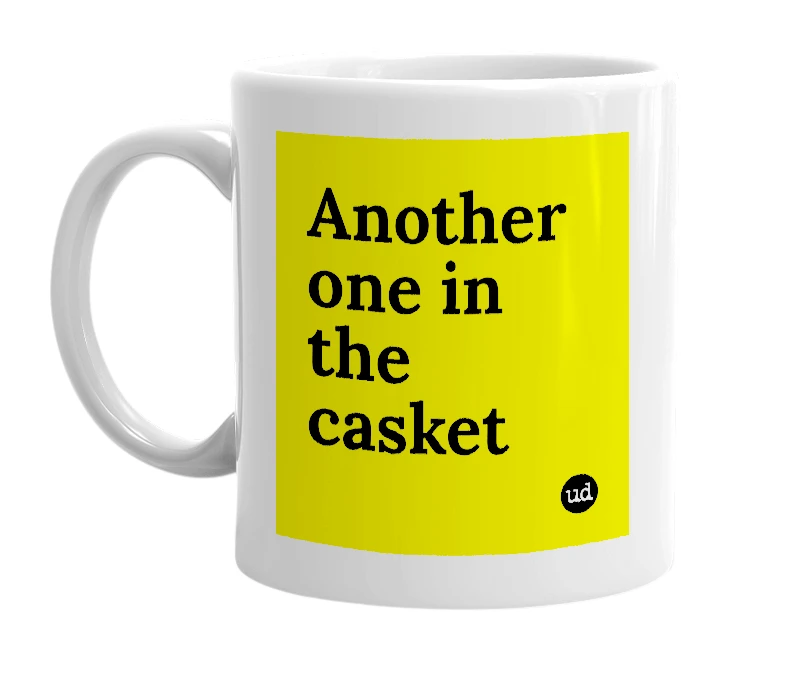 White mug with 'Another one in the casket' in bold black letters