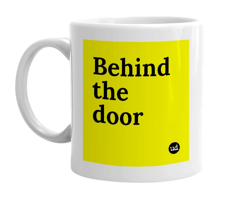 White mug with 'Behind the door' in bold black letters