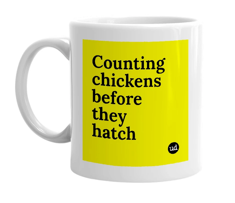 White mug with 'Counting chickens before they hatch' in bold black letters