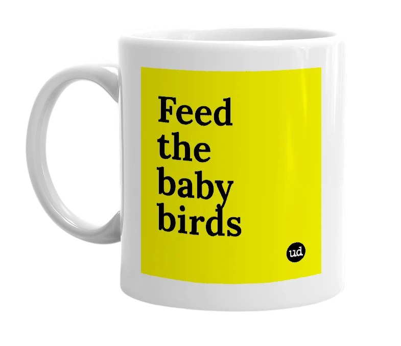 White mug with 'Feed the baby birds' in bold black letters