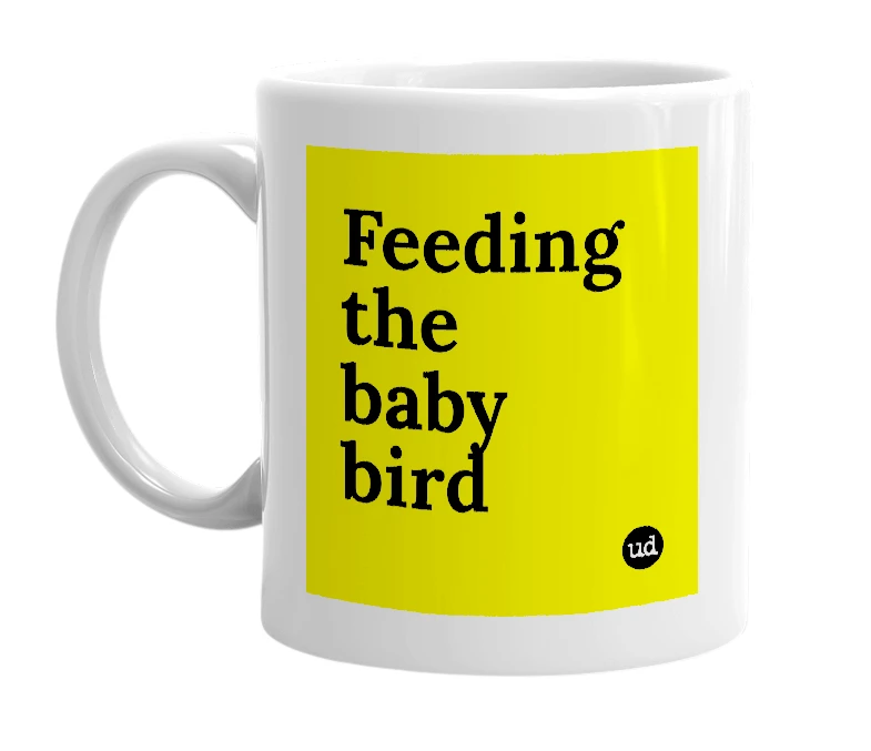 White mug with 'Feeding the baby bird' in bold black letters