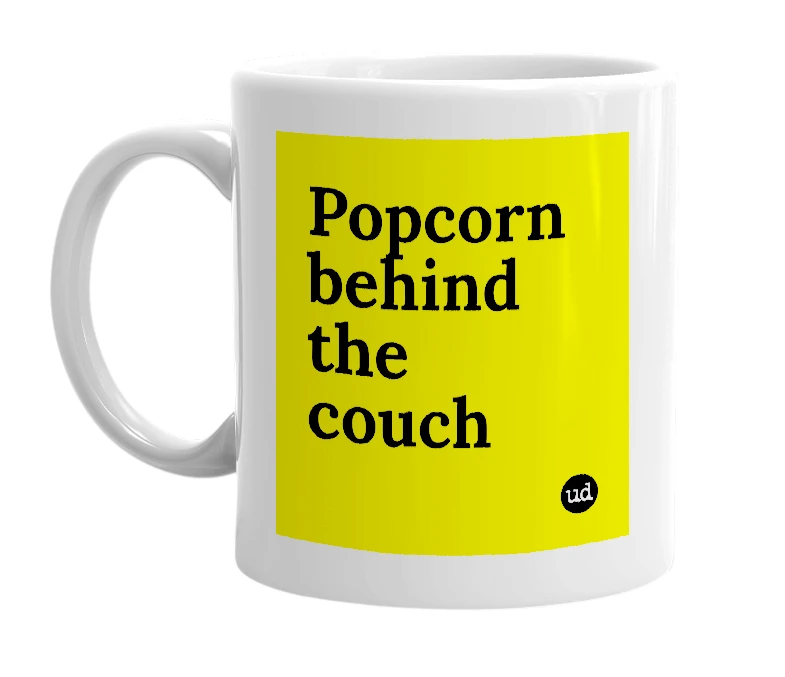 White mug with 'Popcorn behind the couch' in bold black letters