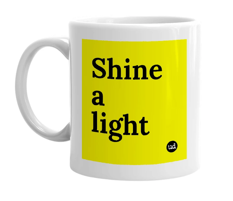 White mug with 'Shine a light' in bold black letters