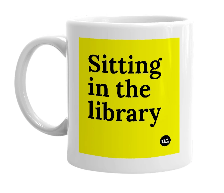 White mug with 'Sitting in the library' in bold black letters