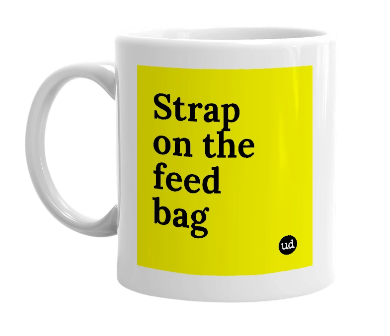White mug with 'Strap on the feed bag' in bold black letters