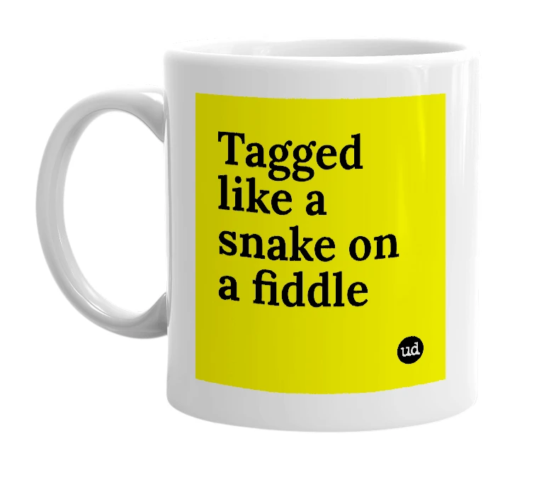 White mug with 'Tagged like a snake on a fiddle' in bold black letters