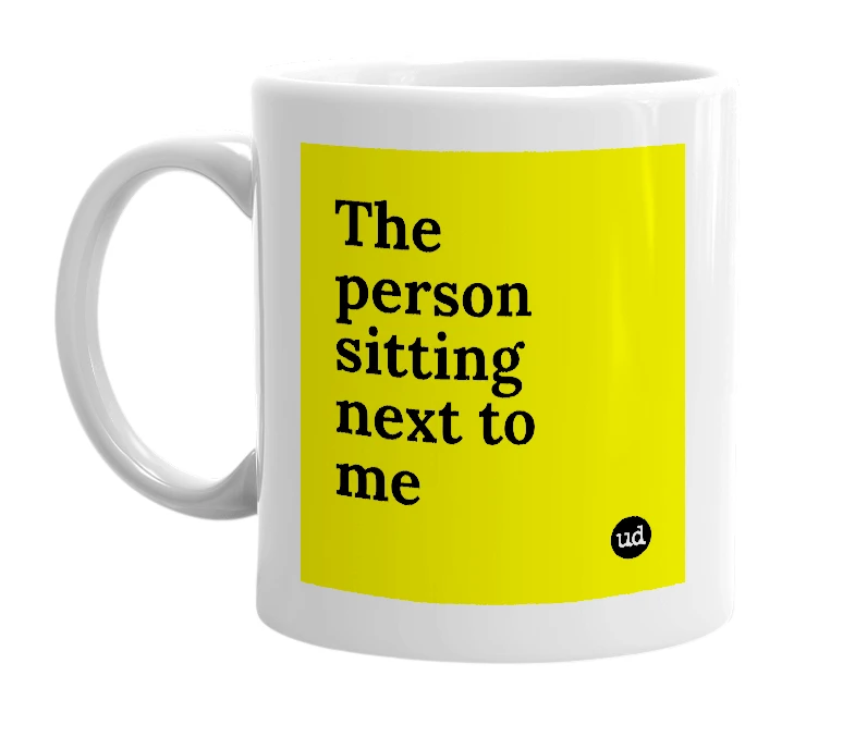 White mug with 'The person sitting next to me' in bold black letters