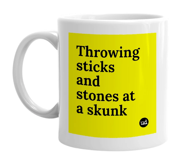 White mug with 'Throwing sticks and stones at a skunk' in bold black letters