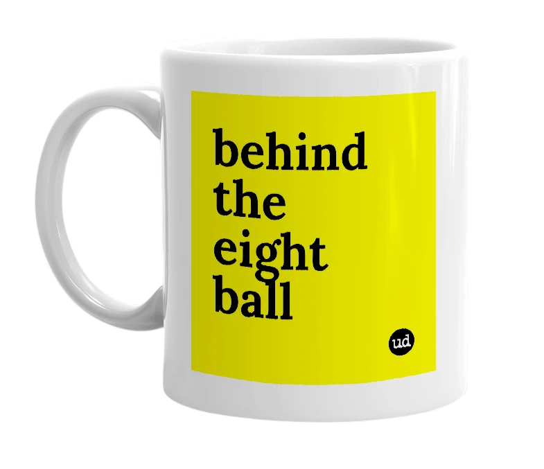 White mug with 'behind the eight ball' in bold black letters