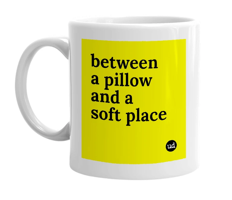 White mug with 'between a pillow and a soft place' in bold black letters