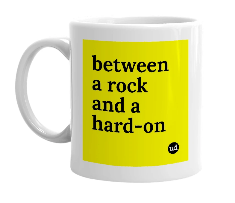 White mug with 'between a rock and a hard-on' in bold black letters