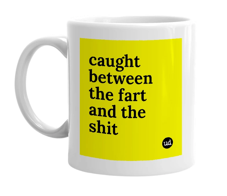 White mug with 'caught between the fart and the shit' in bold black letters