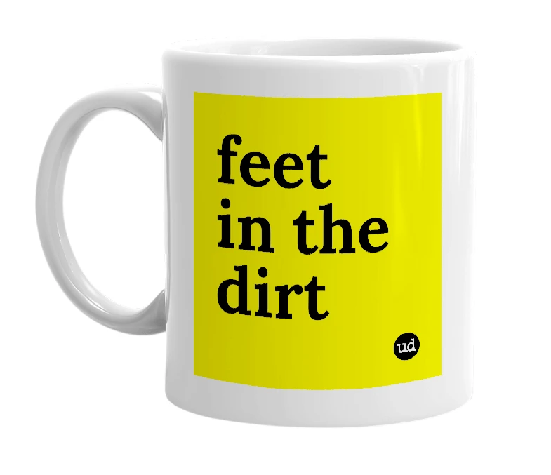 White mug with 'feet in the dirt' in bold black letters