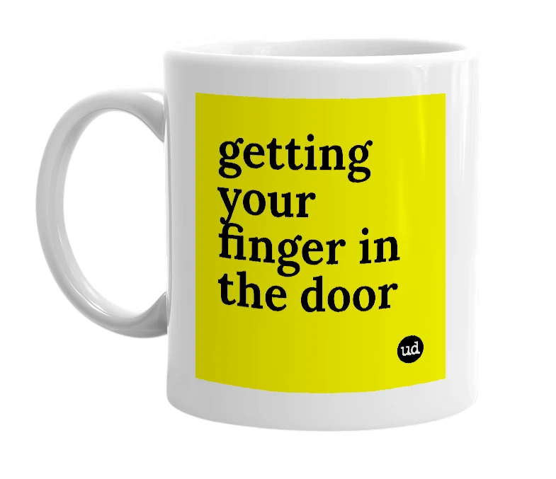 White mug with 'getting your finger in the door' in bold black letters