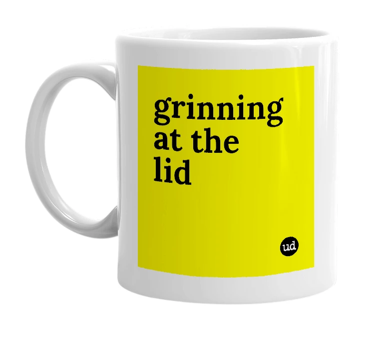 White mug with 'grinning at the lid' in bold black letters