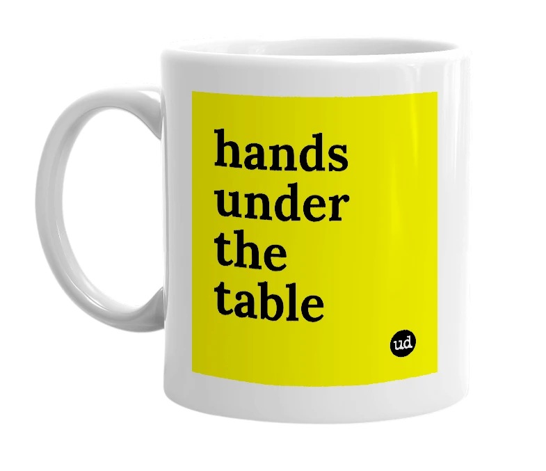 White mug with 'hands under the table' in bold black letters