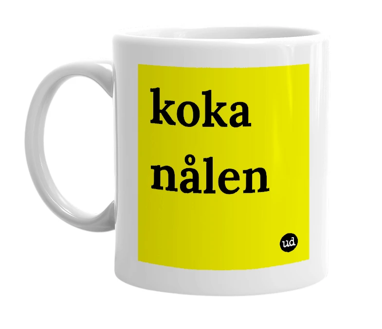 White mug with 'koka nålen' in bold black letters