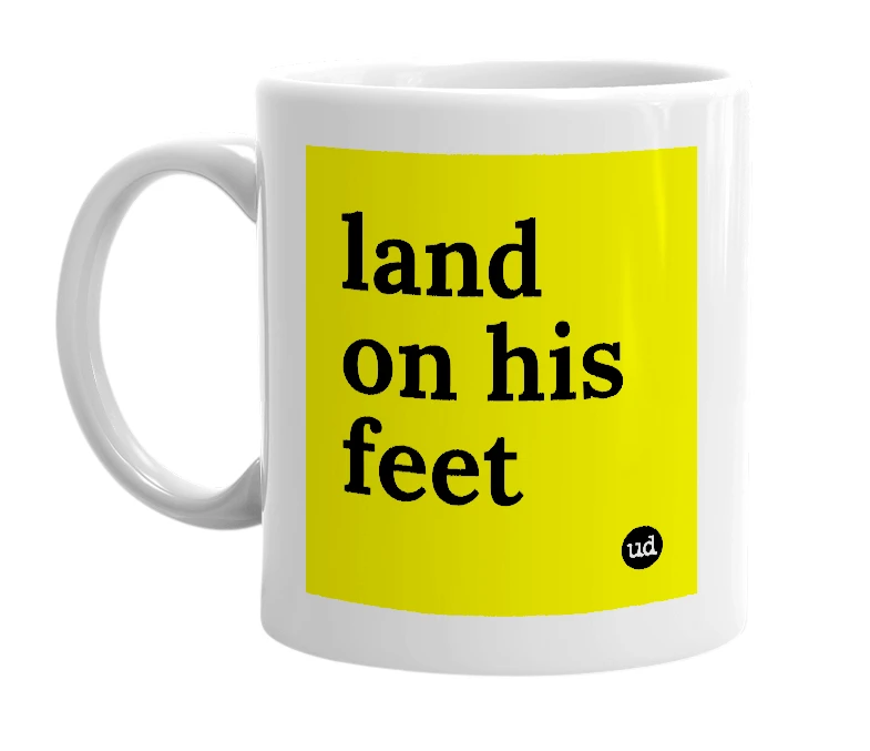 White mug with 'land on his feet' in bold black letters