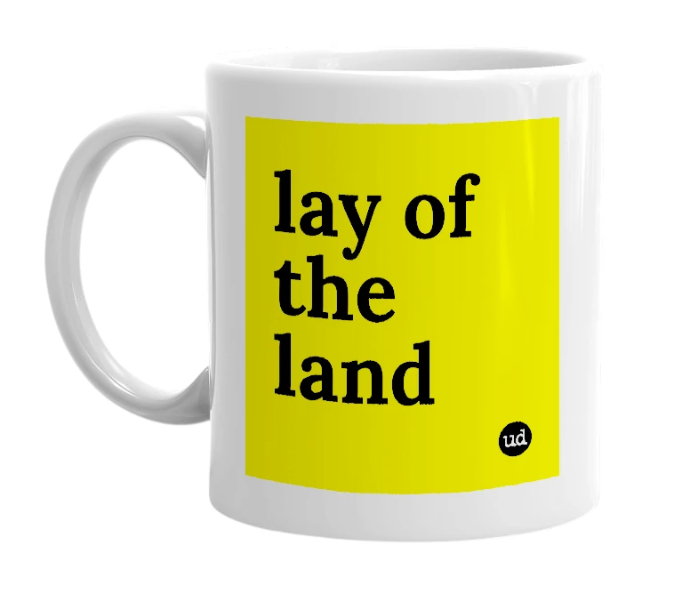 White mug with 'lay of the land' in bold black letters