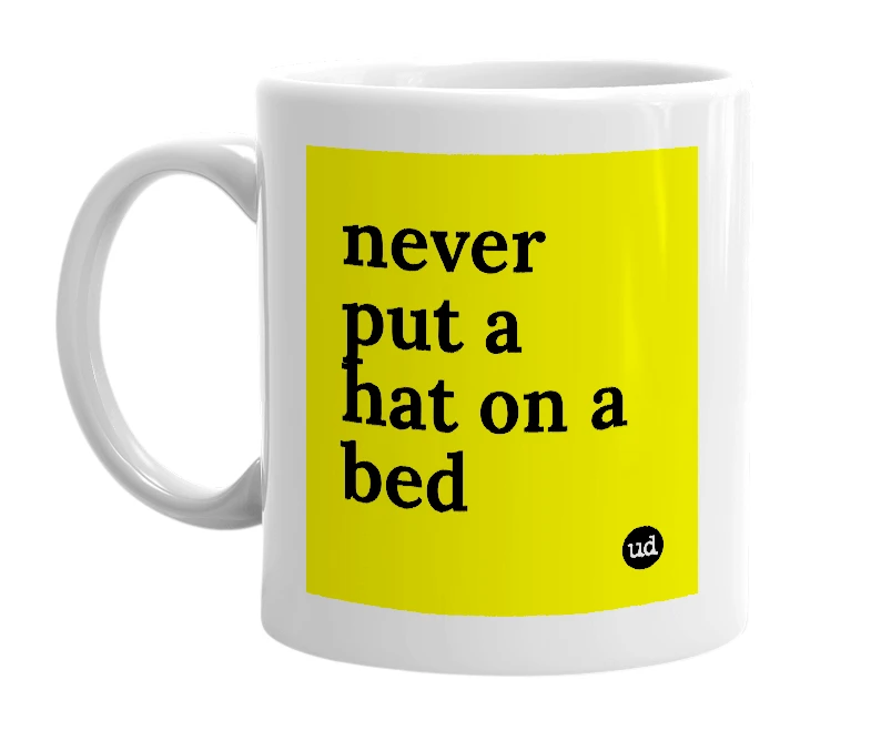 White mug with 'never put a hat on a bed' in bold black letters