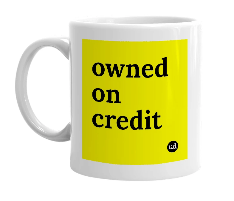 White mug with 'owned on credit' in bold black letters
