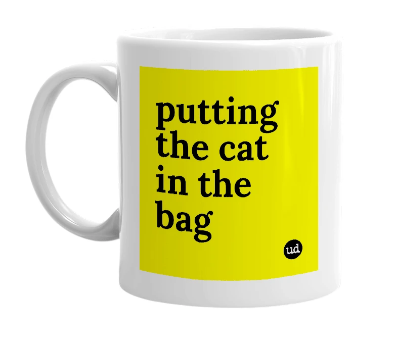 White mug with 'putting the cat in the bag' in bold black letters