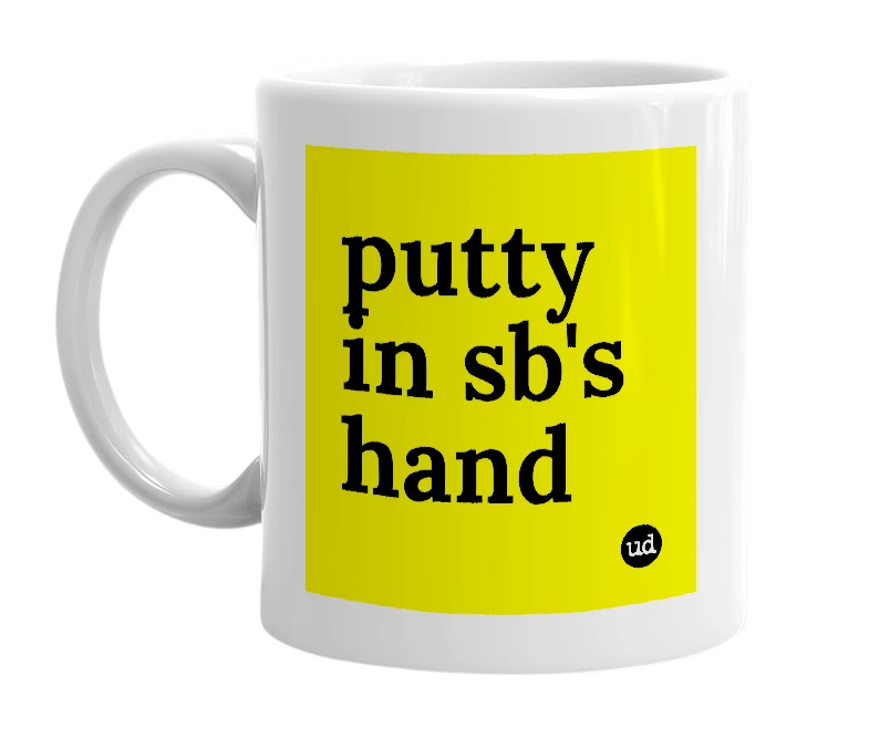 White mug with 'putty in sb's hand' in bold black letters