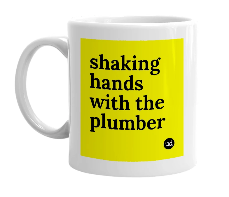White mug with 'shaking hands with the plumber' in bold black letters