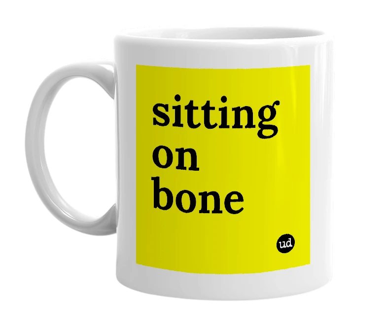 White mug with 'sitting on bone' in bold black letters