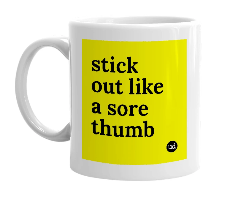 White mug with 'stick out like a sore thumb' in bold black letters