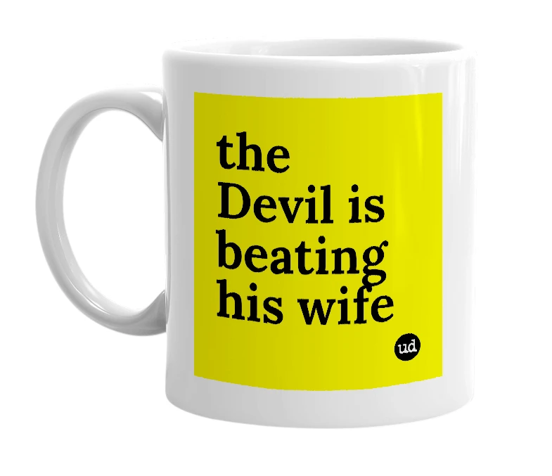 White mug with 'the Devil is beating his wife' in bold black letters