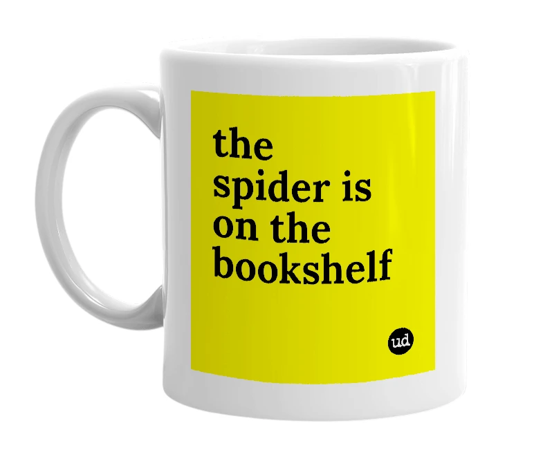 White mug with 'the spider is on the bookshelf' in bold black letters