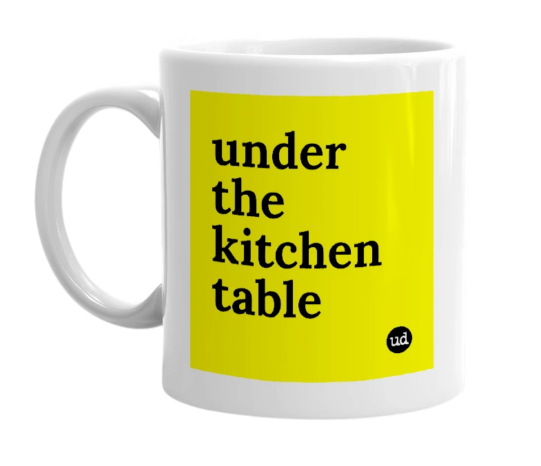 White mug with 'under the kitchen table' in bold black letters