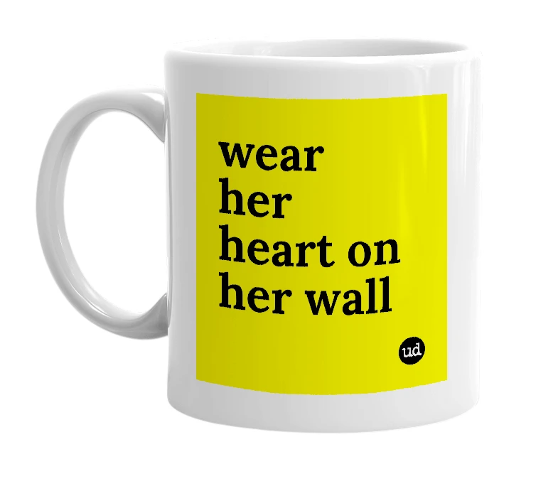 White mug with 'wear her heart on her wall' in bold black letters