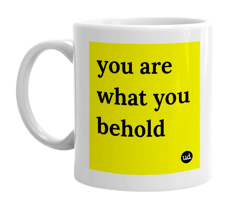 White mug with 'you are what you behold' in bold black letters